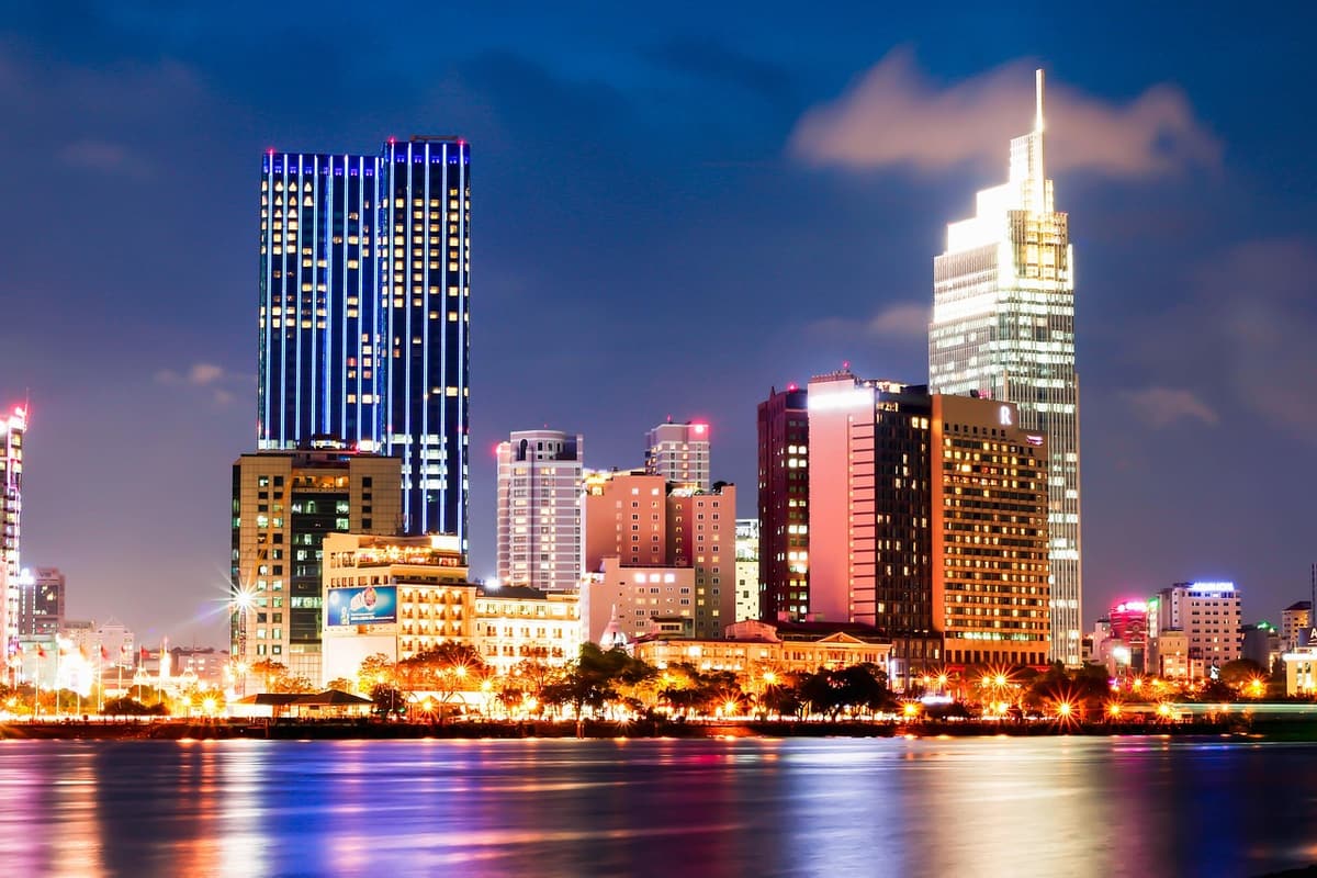 Crowds gather along Bach Dang Wharf on the Saigon River with the city skyline glowing behind them on New Year's Eve