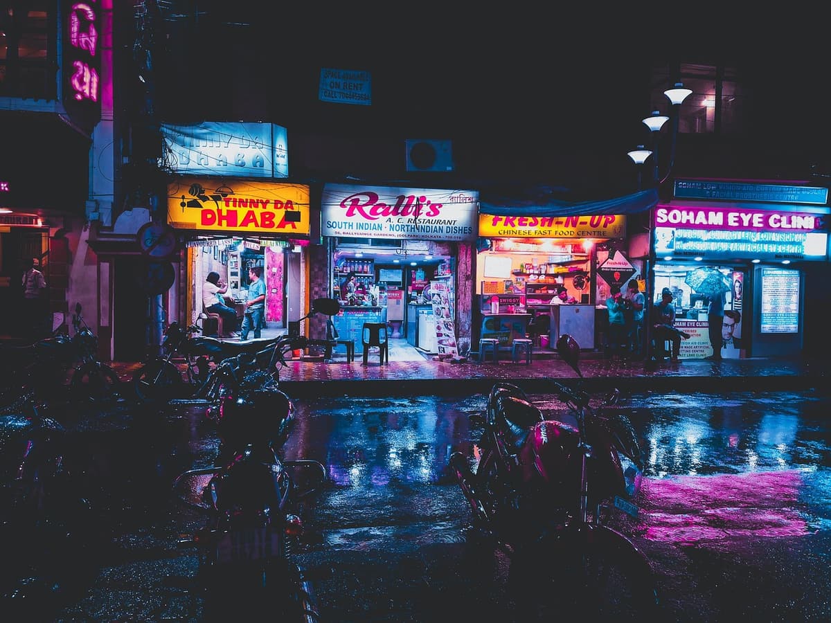 A rooftop bar in District 1 Saigon with low neon lighting, palm trees in planters, and patrons toasting against a backdrop of city lights