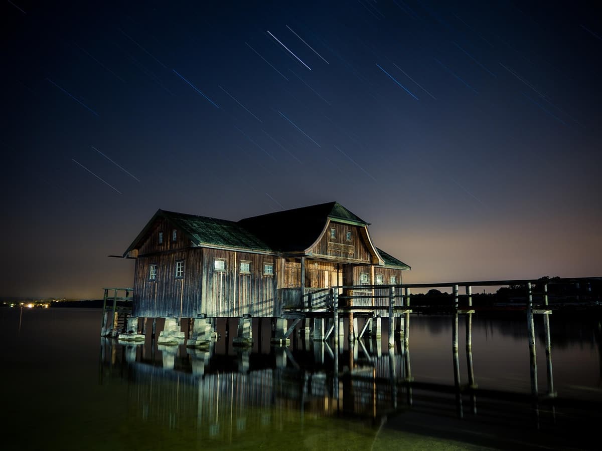 Wooden stilt houses line a calm bay at Ham Ninh fishing village in Phu Quoc with small fishing boats moored along a long wooden pier walking out over shallow seagrass beds