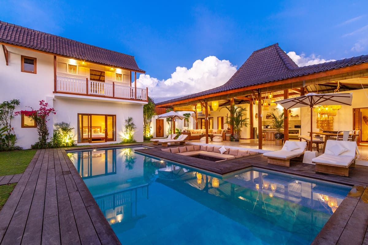 A modern boutique hotel pool with palm trees, wooden loungers, and a soft late-afternoon sun reflected in the calm water