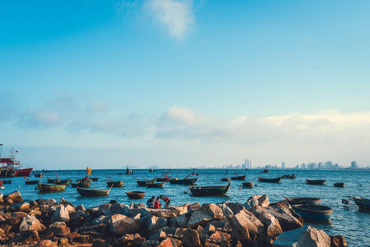 My Khe Beach in Da Nang stretches into the distance with high-rise hotels behind palm trees and small fishing baskets pulled up on the sand