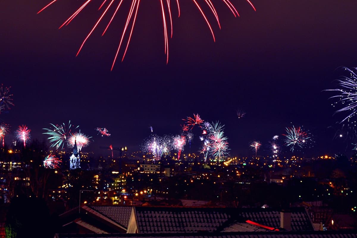 A vibrant burst of New Year's Eve fireworks lights up the Saigon River with the city skyline silhouetted against the colorful sky